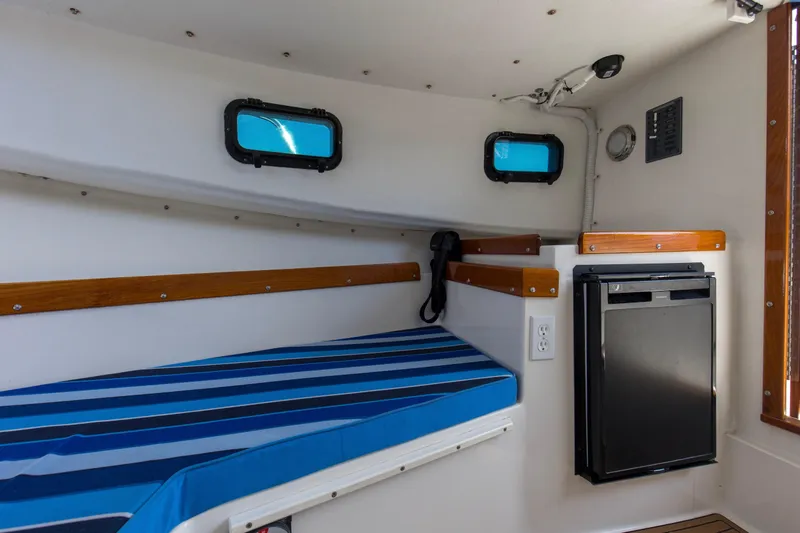 Slide: The Image of 2019 Seaway Seafarer 24 cabin interior with striped bedding and compact refrigerator. - 11