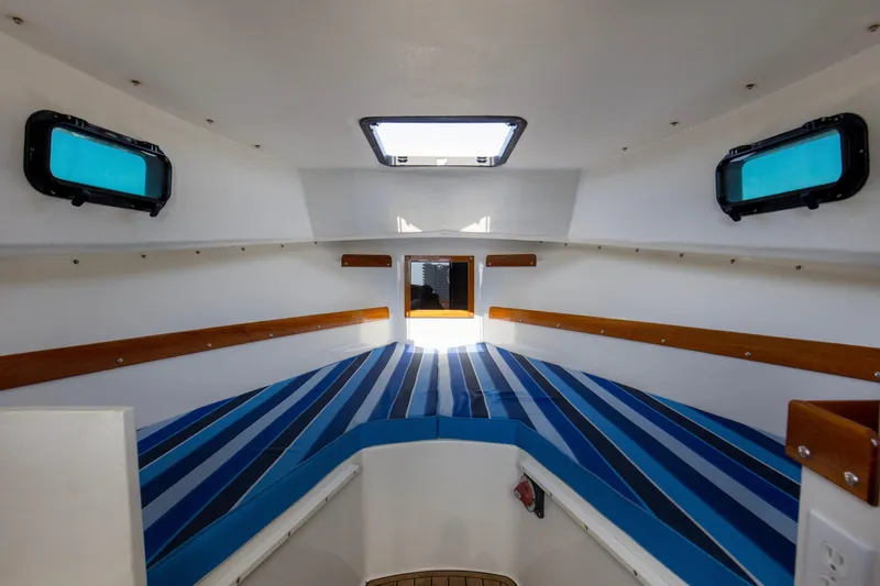Slide: The Image of Interior cabin of 2019 Seaway Seafarer 24 with striped cushions and wooden accents. - 10
