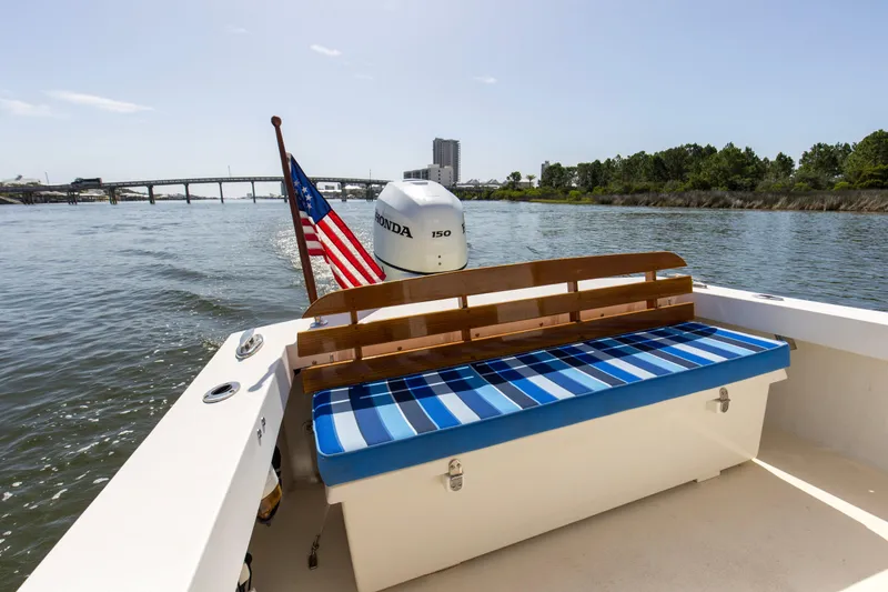 Slide: The Image of 2019 Seaway Seafarer 24 boat with striped seating, American flag, and Honda motor on a scenic river. - 17