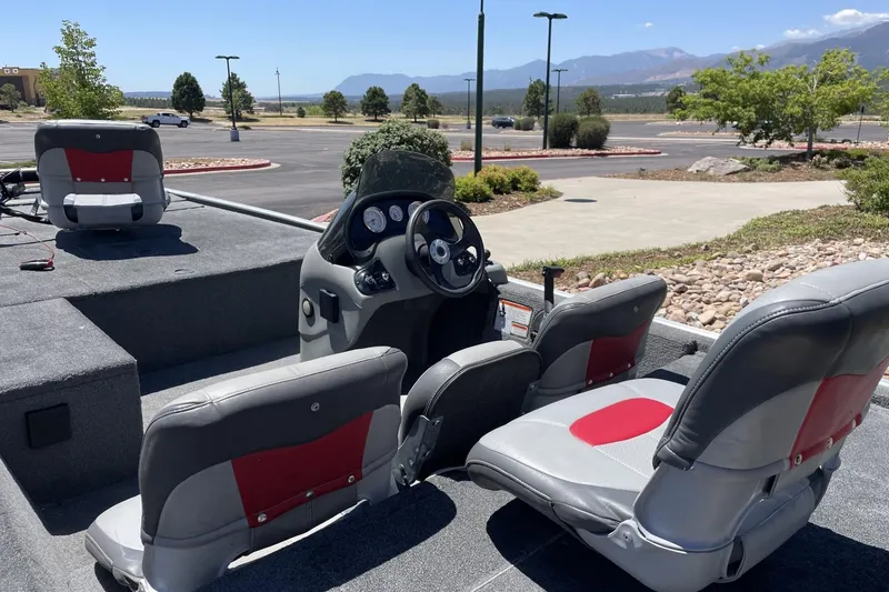 Slide: The Image of 2015 Tracker Pro 170 boat interior with gray and red seating, parked outdoors. - 5