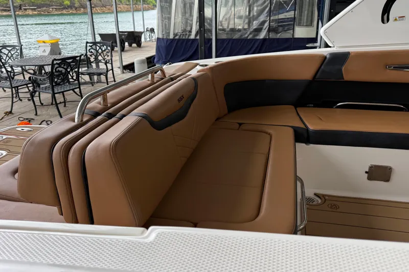 Slide: The Image of 2023 Chaparral 287 SSX boat with tan leather seating, docked by a lakeside. - 2