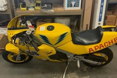 Slide: The Image of Yellow 1987 Apache 47 motorcycle with blue lightning graphics in a garage setting. - 21