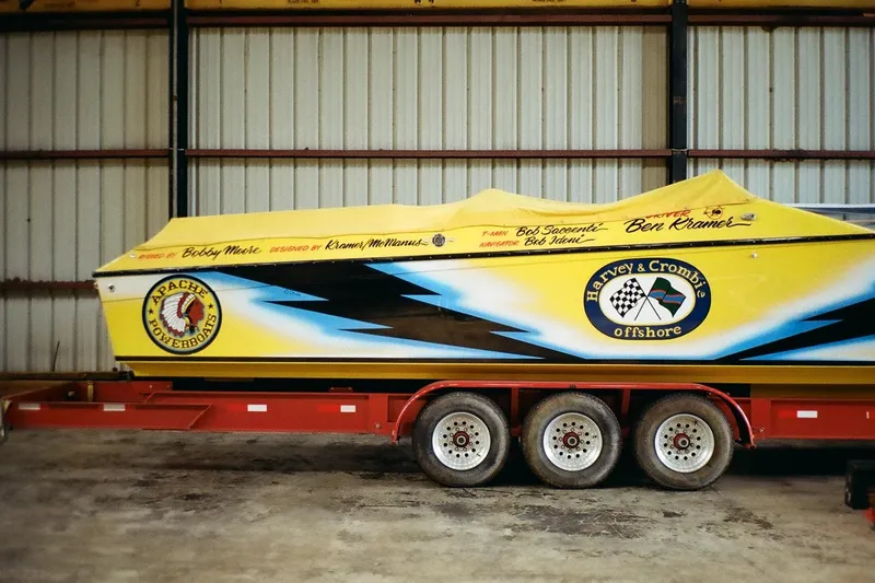 Slide: The Image of Yellow 1987 Apache 47 powerboat on trailer in warehouse, featuring Apache Powerboats logo. - 19