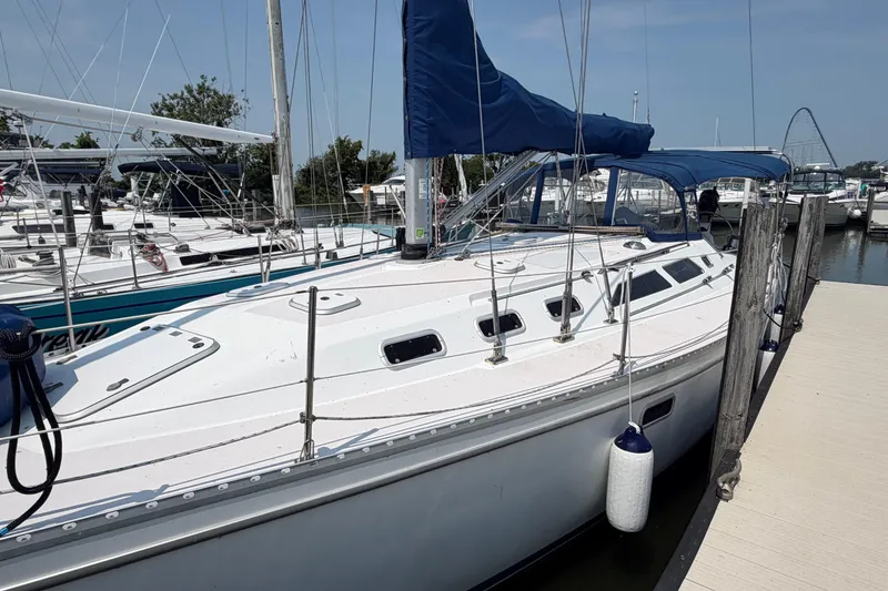 Slide: The Image of 1995 Catalina 400 sailboat docked at marina with blue canopy and white hull. - 2