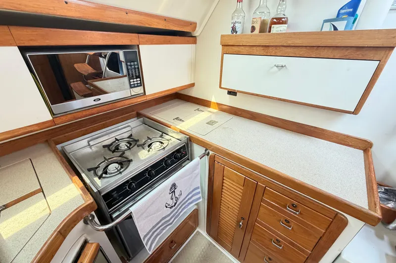 Slide: The Image of 1995 Catalina 400 yacht kitchen with stove, microwave, and wooden cabinetry. - 25