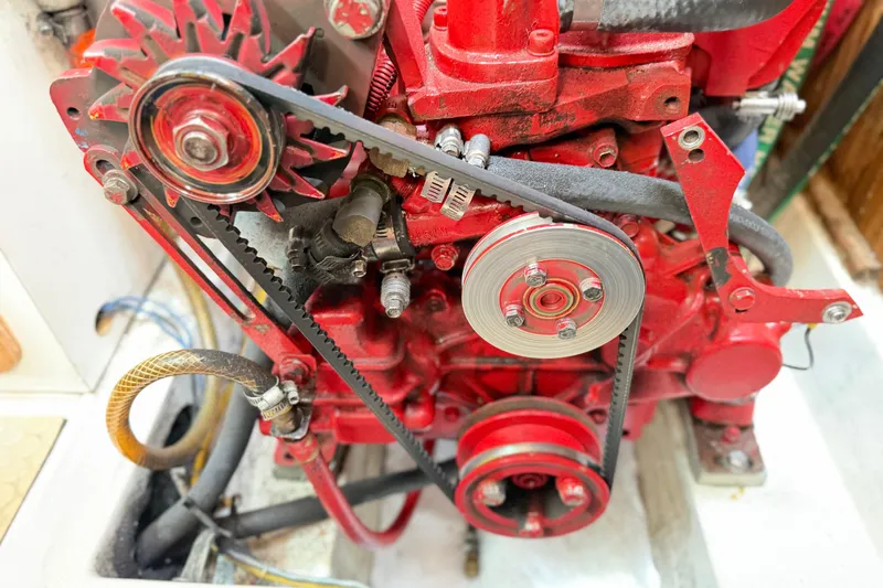 Slide: The Image of Close-up of a red engine in a 1995 Catalina 400 sailboat, showcasing belts and pulleys. - 43