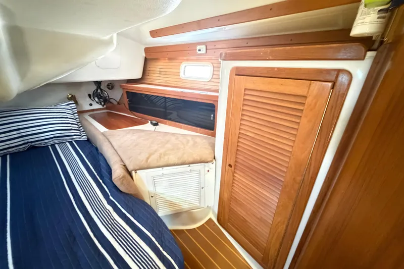 Slide: The Image of Interior cabin of a 1995 Catalina 400 sailboat with wood paneling and striped bedding. - 33