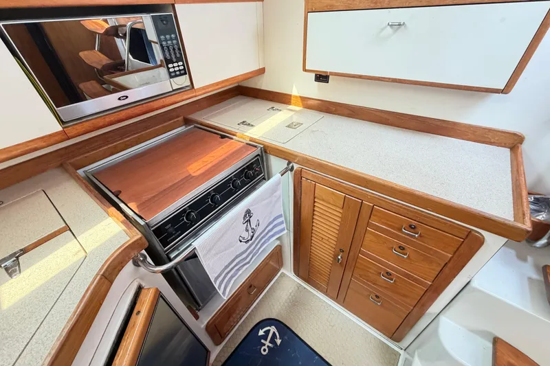 Slide: The Image of Cozy galley kitchen in a 1995 Catalina 400 sailboat, featuring wood cabinetry and modern appliances. - 23
