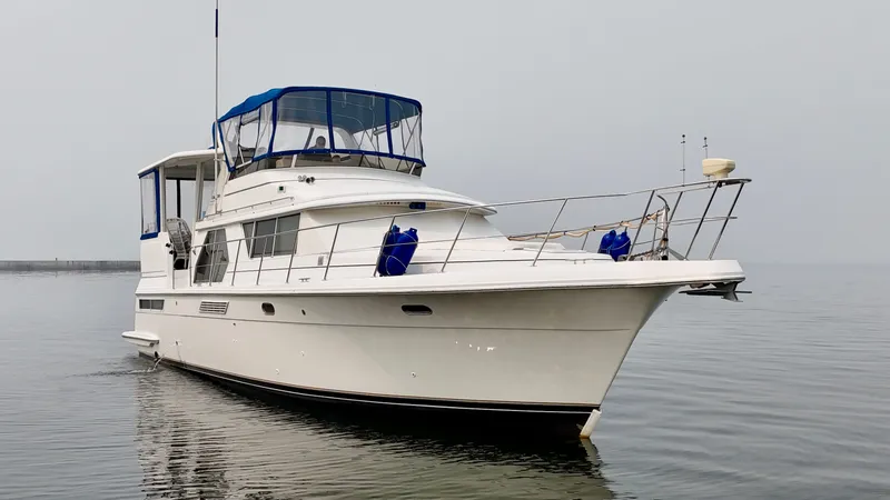 Slide: The Image of 1997 Carver 445 Aft Cabin Motor Yacht on calm water with blue canopy. - 6