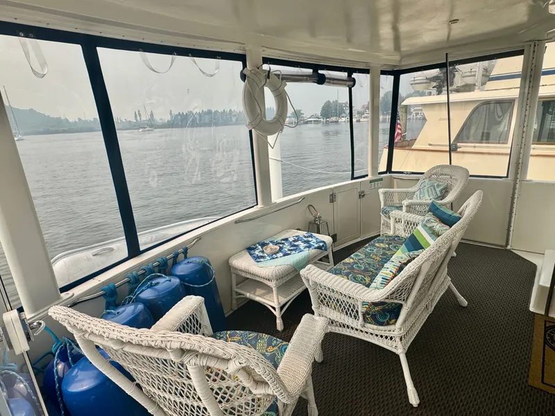 Slide: The Image of A cozy seating area on a yacht with wicker furniture and cushions, surrounded by large windows. - 21