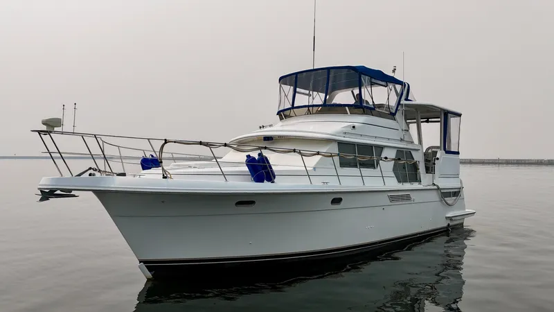 Slide: The Image of 1997 Carver 445 Aft Cabin Motor Yacht on calm water with blue canopy and railing. - 8