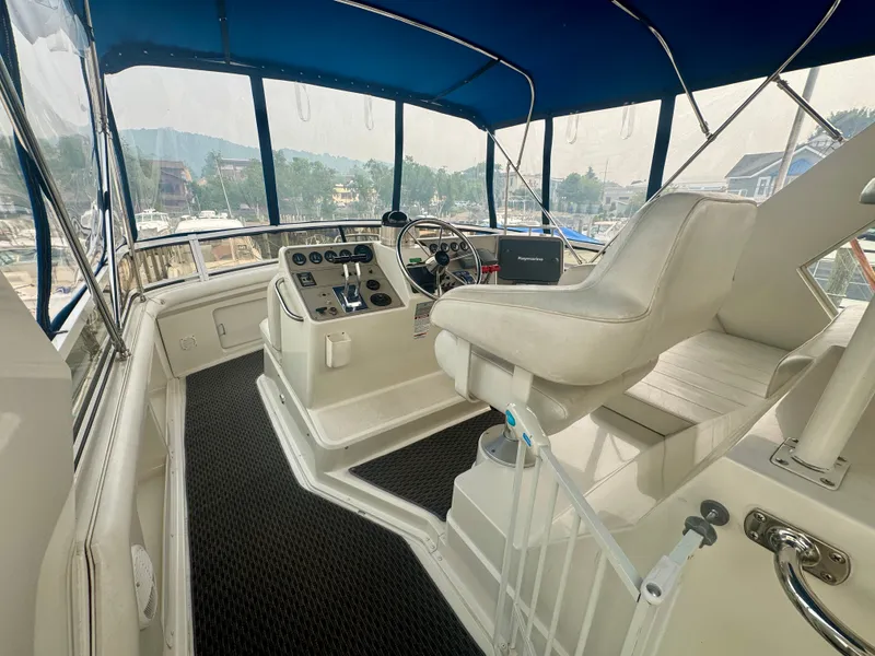 Slide: The Image of The image shows the helm of a 1997 Carver 445 Aft Cabin Motor Yacht with white seats and blue canopy. - 24