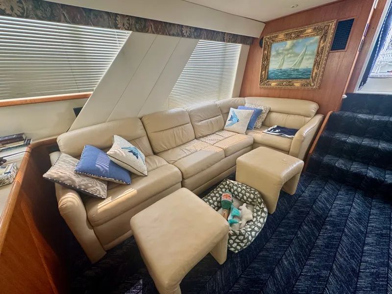Slide: The Image of The image shows the interior of a 1997 Carver 445 Aft Cabin Motor Yacht. A beige leather sofa with cushions is next to a window. A painting hangs on the wall. - 31