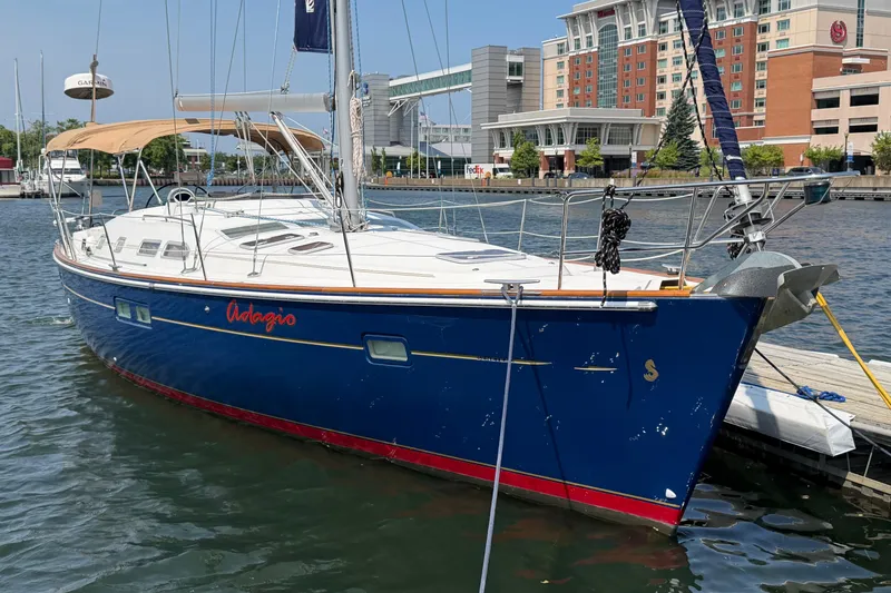 The Image of Sleek 2006 Beneteau 423 sailboat docked in a marina, featuring a blue hull and tan canopy. - 0