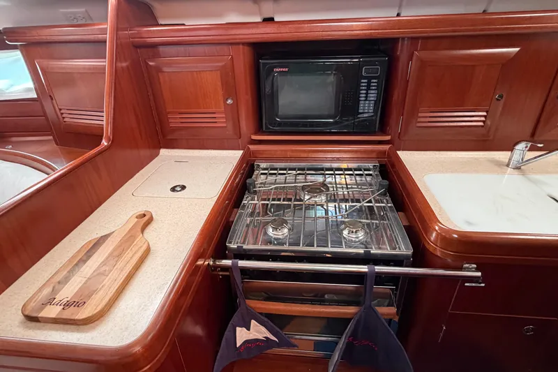 Slide: The Image of Galley kitchen in 2006 Beneteau 423 yacht with stove, microwave, and wooden cabinetry. - 32