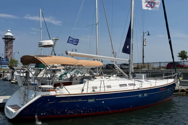 Slide: The Image of 2006 Beneteau 423 sailboat docked at marina with flags and lighthouse in background. - 6