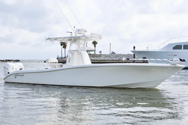 Slide: The Image of 2009 Yellowfin 29 Offshore boat on calm water, showcasing sleek design and powerful engines. - 2
