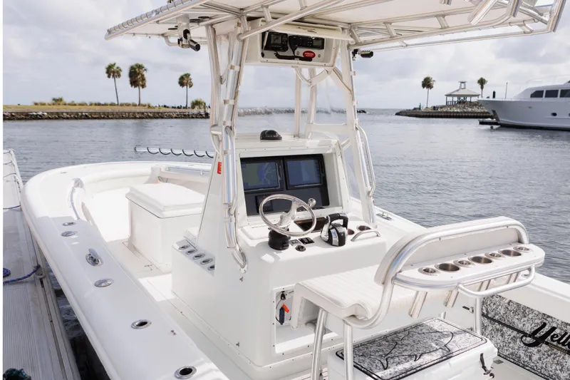 Slide: The Image of 2009 Yellowfin 29 Offshore boat with modern helm, docked near palm trees and water. - 17