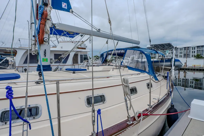 Slide: The Image of 2004 Island Packet 370 sailboat docked at marina, featuring blue canvas and rigging. - 31