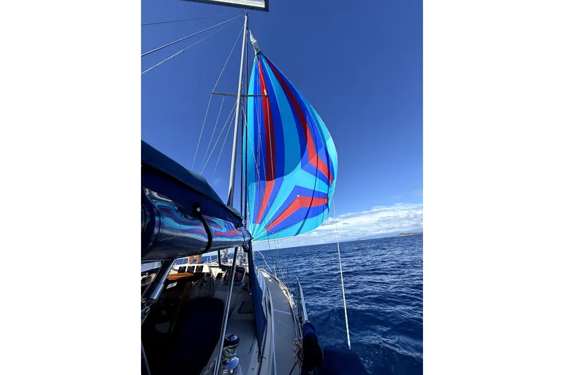 Slide: The Image of Sailing on a 2004 Island Packet 370 with vibrant blue and red spinnaker against clear skies. - 40