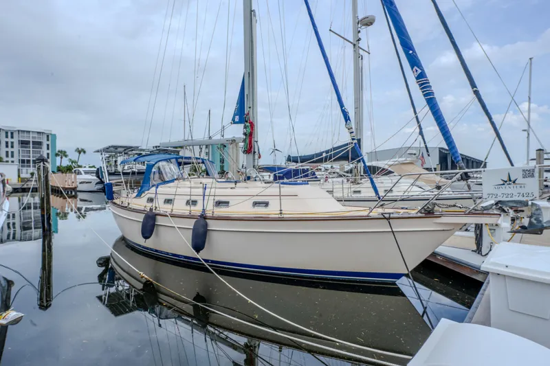 The Image of 2004 Island Packet 370 sailboat docked at a marina, featuring blue accents and calm waters. - 0