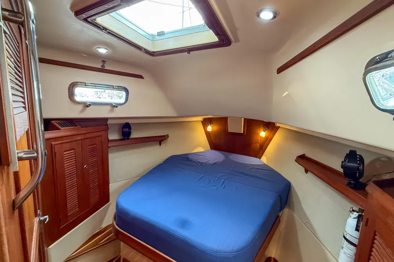 Slide: The Image of Cozy cabin interior of 2004 Island Packet 370 sailboat with blue bedding and wooden accents. - 16