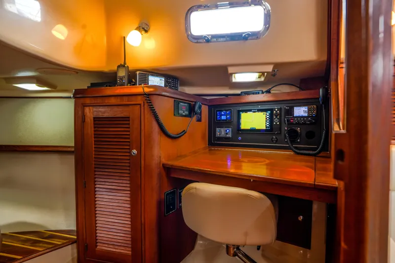 Slide: The Image of Navigation station inside 2004 Island Packet 370 sailboat, featuring wooden cabinetry and modern equipment. - 22