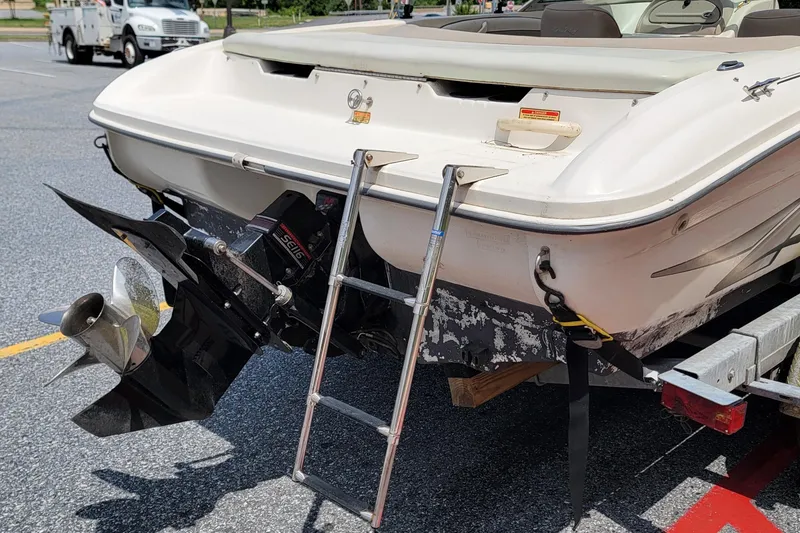 Slide: The Image of 2003 Sea Ray 182 Bow Rider boat with ladder and propeller, parked on a trailer. - 4