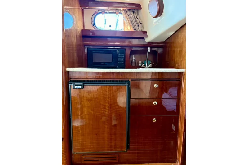 Slide: The Image of 2001 Apreamare 9 M yacht interior with kitchenette, featuring microwave, fridge, and wooden cabinetry. - 19