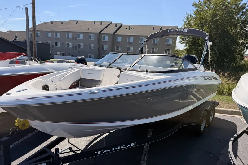 Slide: The Image of 2024 Tahoe 210 S boat on trailer, parked outdoors, with buildings in the background. - 2