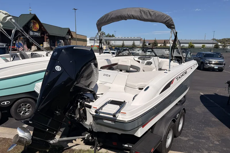 Slide: The Image of 2024 Tahoe 210 S boat with outboard motor on a trailer in a parking lot. - 4