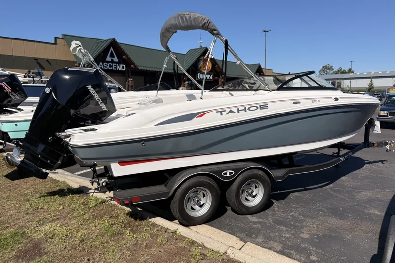 The Image of 2024 Tahoe 210 S boat on trailer, displayed outdoors at a dealership. - 1