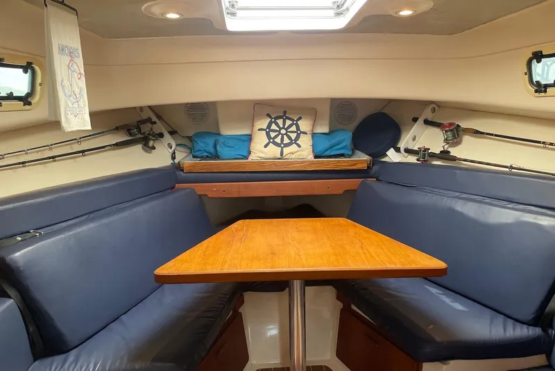 Slide: The Image of 1999 Mainship Pilot 30 cabin interior with blue seating, wooden table, and nautical decor. - 17