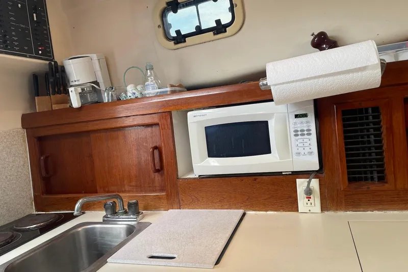 Slide: The Image of 1999 Mainship Pilot 30 galley with microwave, sink, and wooden cabinetry. - 13