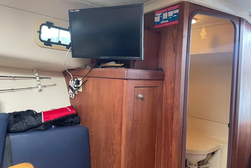 Slide: The Image of Interior of 1999 Mainship Pilot 30 boat with TV, wooden cabinetry, and seating area. - 18
