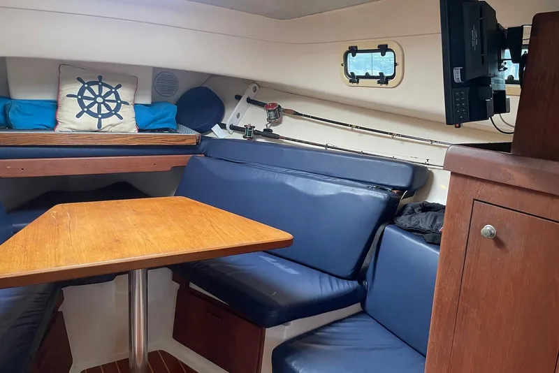 Slide: The Image of Interior of 1999 Mainship Pilot 30 boat with blue seating and wooden table. - 16
