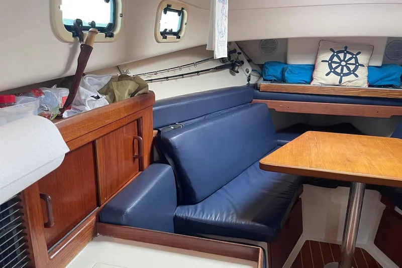 Slide: The Image of 1999 Mainship Pilot 30 cabin interior with blue seating, wooden table, and nautical decor. - 15