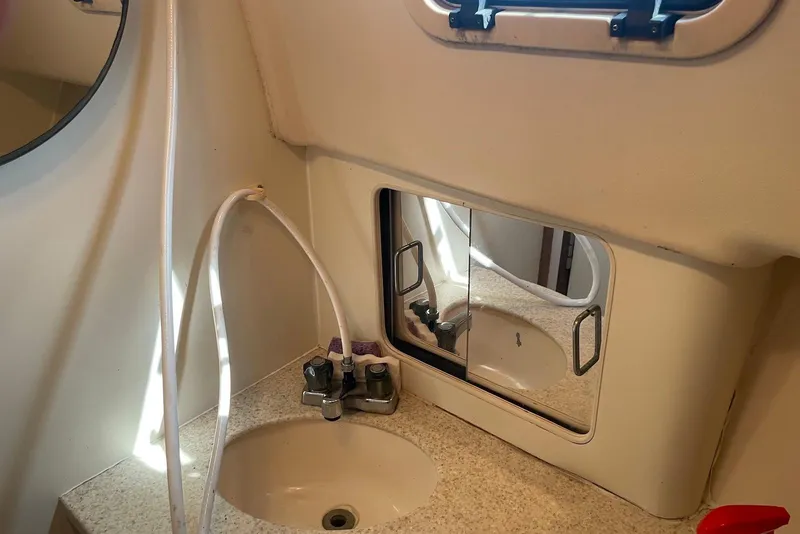 Slide: The Image of Bathroom sink area in a 1999 Mainship Pilot 30 boat, featuring a mirror and faucet. - 19