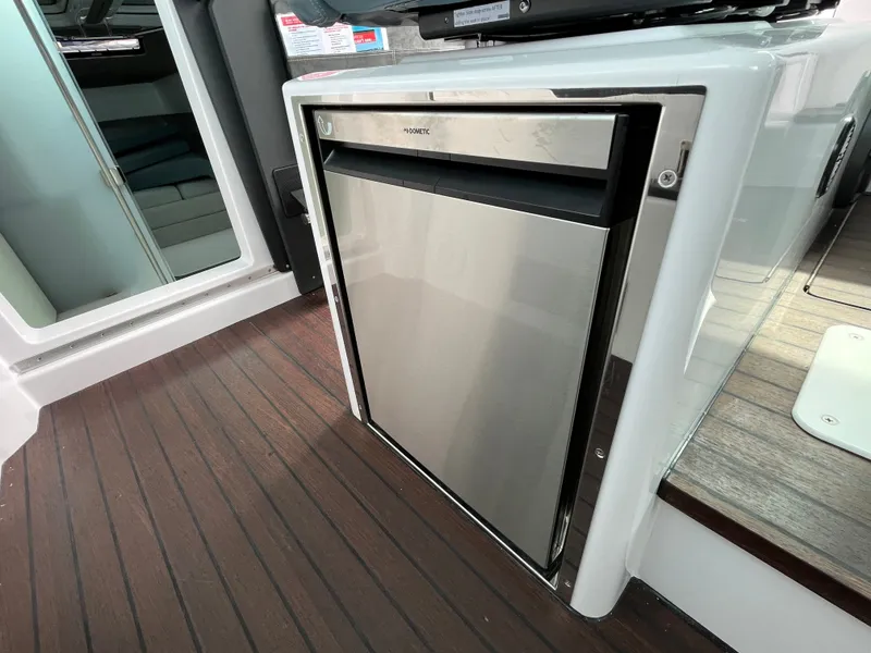 Slide: The Image of A modern refrigerator in a 2024 Axopar 37 XC Cross Cabin, surrounded by sleek wood flooring. - 16