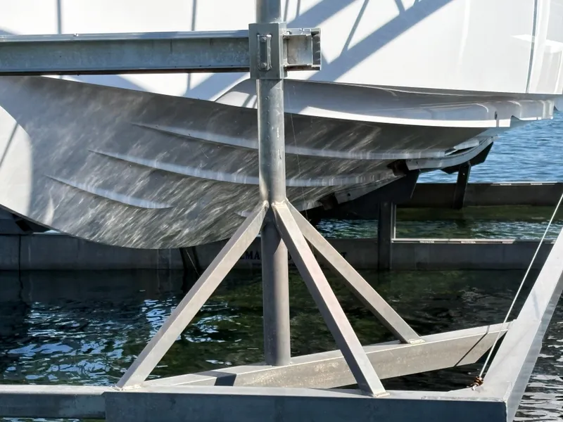 Slide: The Image of A 2024 Axopar 37 XC Cross Cabin on a boat lift above the water. - 23