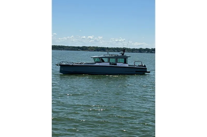 Slide: The Image of 2024 Axopar 37 XC Cross Cabin boat on calm water under clear sky. - 30