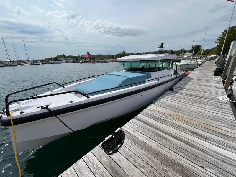 The Image of A 2024 Axopar 37 XC Cross Cabin docked at a wooden pier in a calm harbor. - 0