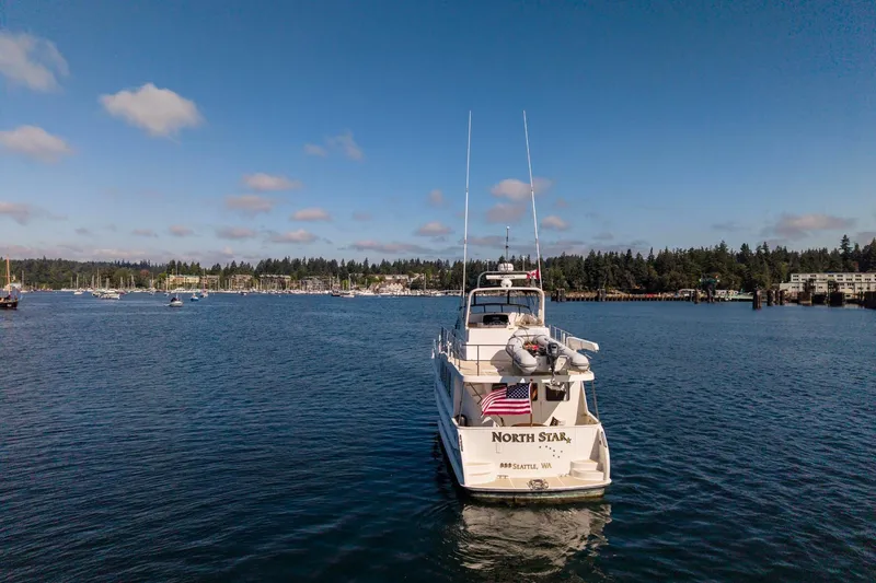 Slide: The Image of North Pacific 52 yacht "North Star" on calm waters, 2006 model, with scenic shoreline backdrop. - 57