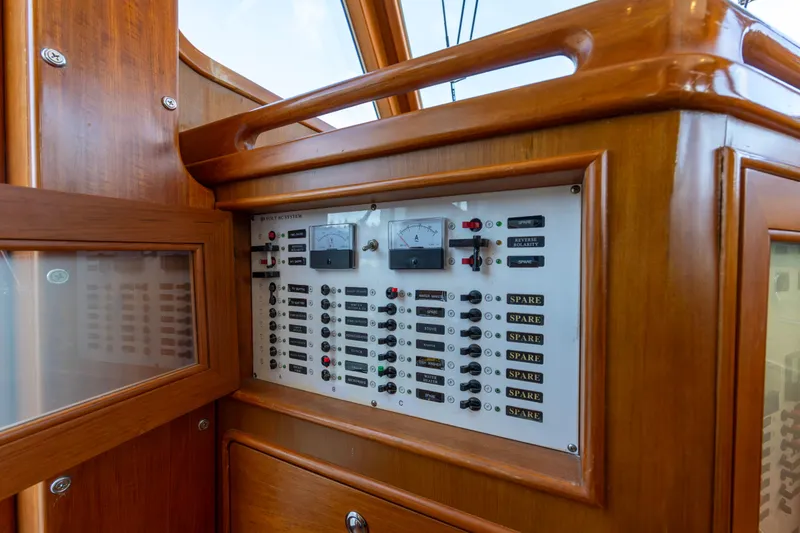 Slide: The Image of Electrical panel inside a 2006 North Pacific 52 yacht, featuring wooden cabinetry and labeled switches. - 35