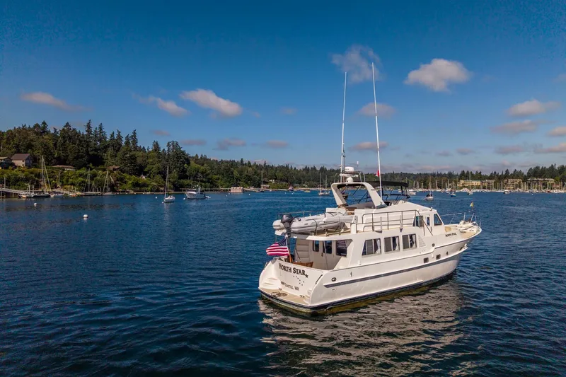 Slide: The Image of 2006 North Pacific 52 yacht on serene water with scenic forested shoreline. - 58