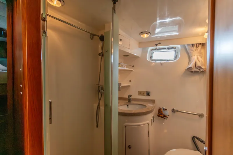 Slide: The Image of Bathroom interior of 2006 North Pacific 52 yacht, featuring shower, sink, and porthole window. - 20