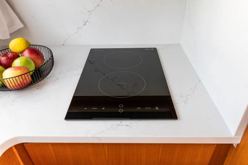 Slide: The Image of Modern kitchen with induction cooktop and fruit basket on marble countertop. - 26