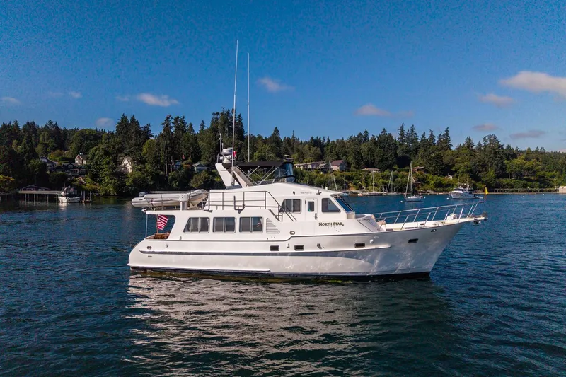 Slide: The Image of 2006 North Pacific 52 yacht on serene water with lush green shoreline. - 59