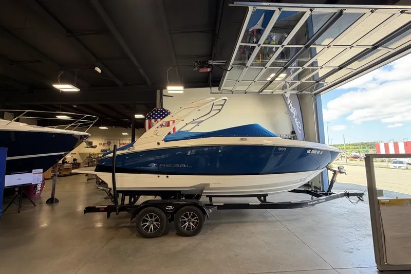 The Image of 2021 Regal LS4 Surf boat in showroom, blue and white design, on trailer. - 0