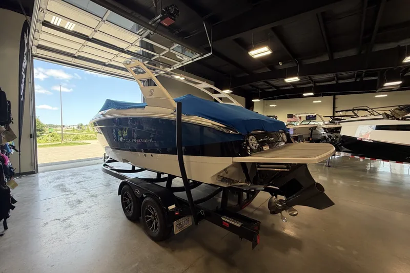 Slide: The Image of 2021 Regal LS4 Surf boat in showroom, blue cover, on trailer, rear view. - 5